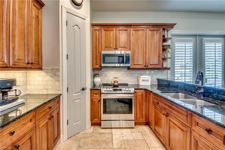 Kitchen with sink, appliances with stainless steel finishes, dark stone counters, and light tile patterned floors