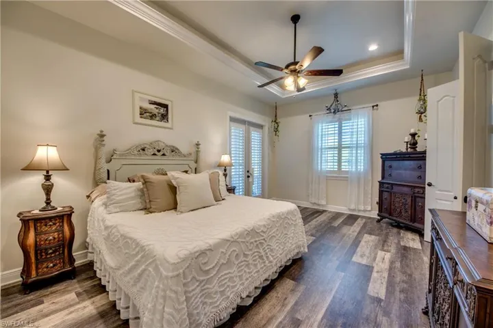 Bedroom featuring dark hardwood / wood-style floors, ceiling fan, and a raised ceiling
