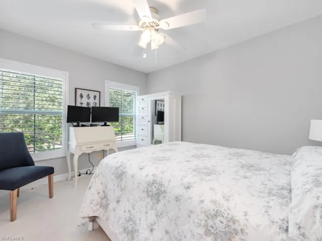 Bedroom with light carpet, multiple windows, and ceiling fan