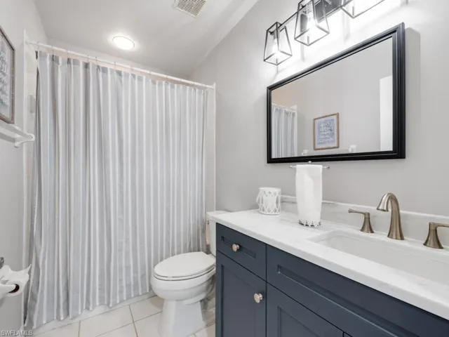 Bathroom with walk in shower, vanity, toilet, and tile patterned floors