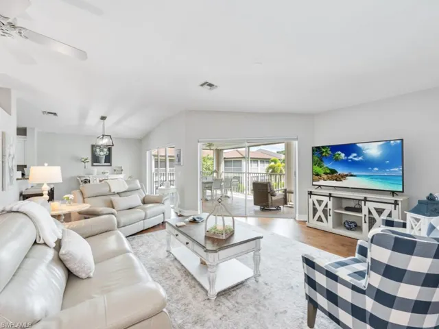 Living room featuring ceiling fan, vaulted ceiling, and light hardwood / wood-style floors