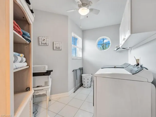 Laundry area with cabinets, radiator, independent washer and dryer, light tile patterned floors, and ceiling fan