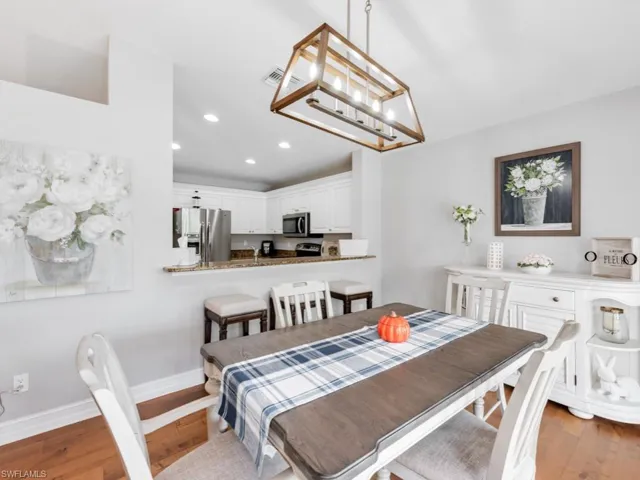 Dining room with light wood-type flooring and a notable chandelier