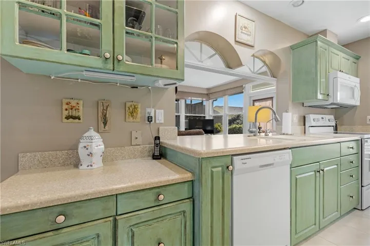 Kitchen with sink, light tile patterned floors, white appliances, and kitchen peninsula