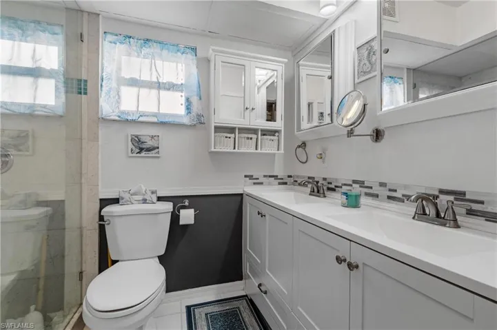 Bathroom featuring vanity, a tile shower, backsplash, and toilet