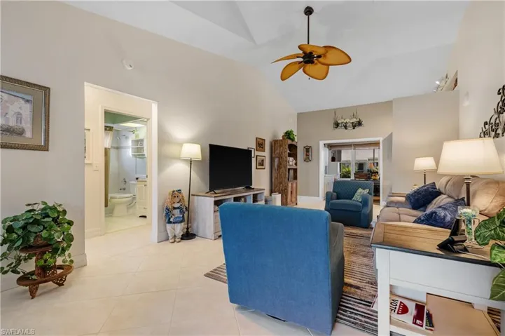 Living room featuring high vaulted ceiling, ceiling fan, and light tile patterned flooring
