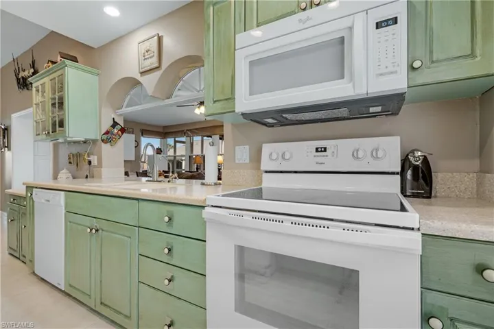 Kitchen featuring sink, white appliances, and green cabinetry