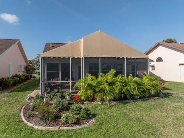 Rear view of house featuring a sunroom and a yard