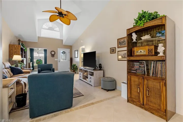Tiled living room with high vaulted ceiling and ceiling fan