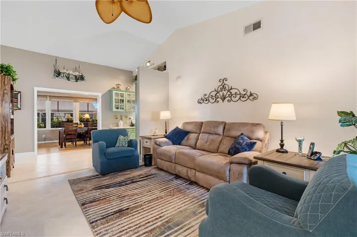 Tiled living room with ceiling fan and lofted ceiling