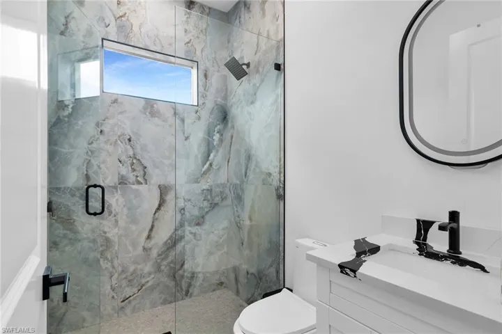 Full bathroom featuring a marble finish shower and vanity