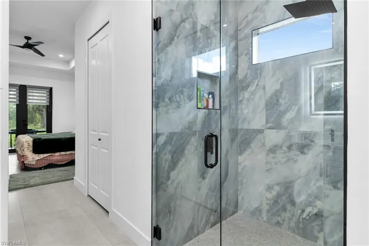 Bathroom featuring plenty of natural light, ensuite bath, a marble finish shower, and a ceiling fan