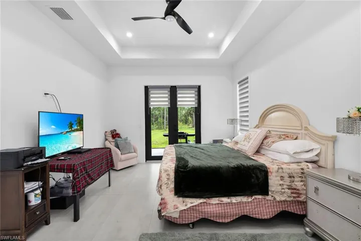 Bedroom with a raised ceiling, french doors, access to outside, a ceiling fan, and recessed lighting