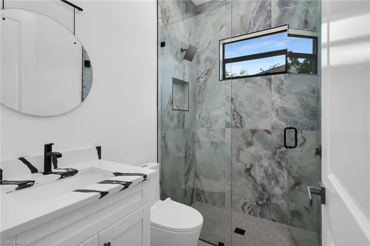Bathroom with a marble finish shower and vanity