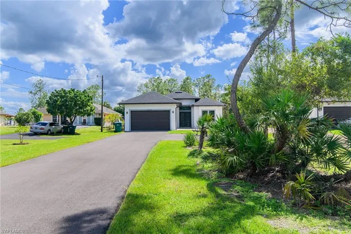 View of front of property featuring a front yard, asphalt driveway, a garage, and stucco siding