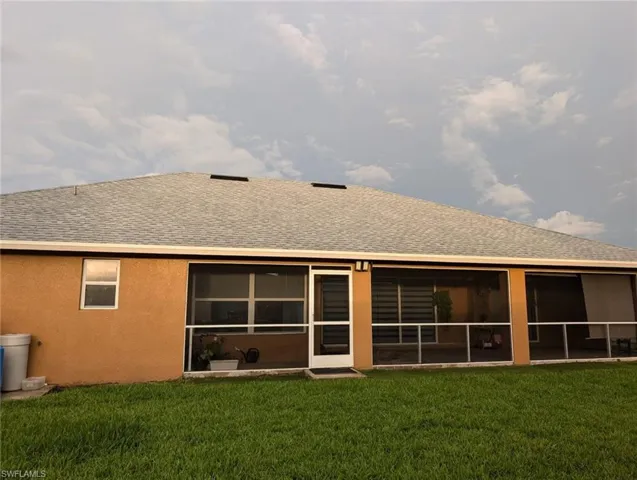 Back of property with a sunroom and a lawn