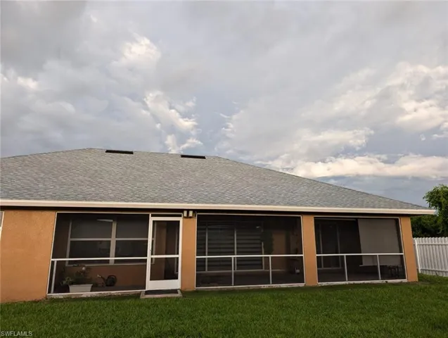 Back of property with a lawn and a sunroom