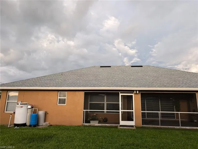 Rear view of house featuring a sunroom and a yard