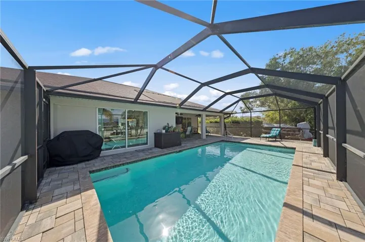 Outdoor pool with a sunroom, glass enclosure, a patio area, and area for grilling
