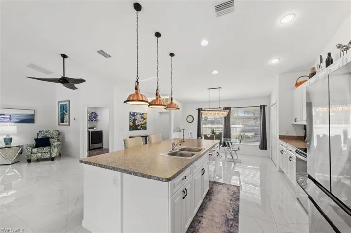 Kitchen featuring white cabinetry, a center island with sink, stainless steel appliances, open floor plan, and a high ceiling
