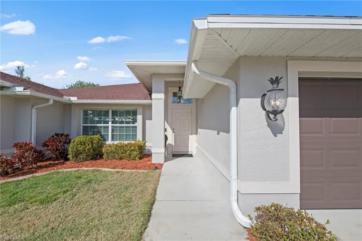 Property entrance with stucco siding, a yard, and an attached garage