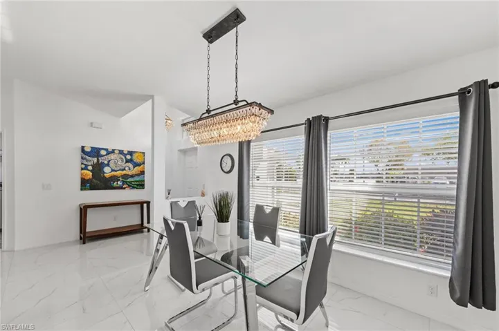 Dining space with light marble finish flooring and a chandelier