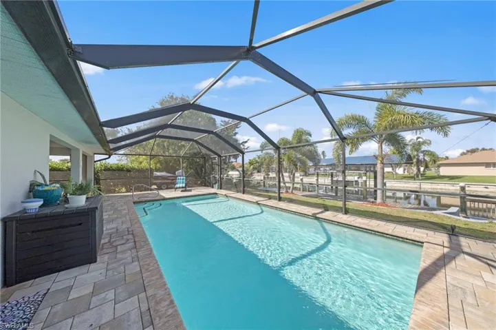 Outdoor pool featuring a sunroom, a patio area, and glass enclosure