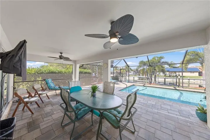 View of patio with a lanai, a ceiling fan, a sunroom, an outdoor pool, and outdoor dining space