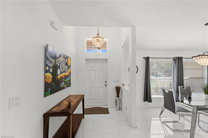 Foyer entrance featuring a chandelier and light marble finish flooring
