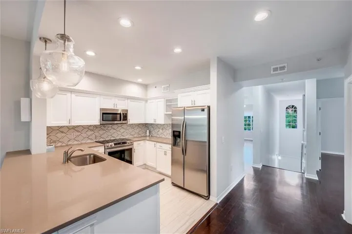 Kitchen featuring appliances with stainless steel finishes, tasteful backsplash, white cabinets, wood finished floors, and recessed lighting