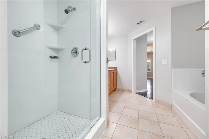 Bathroom with a stall shower, tile patterned flooring, a garden tub, and vanity