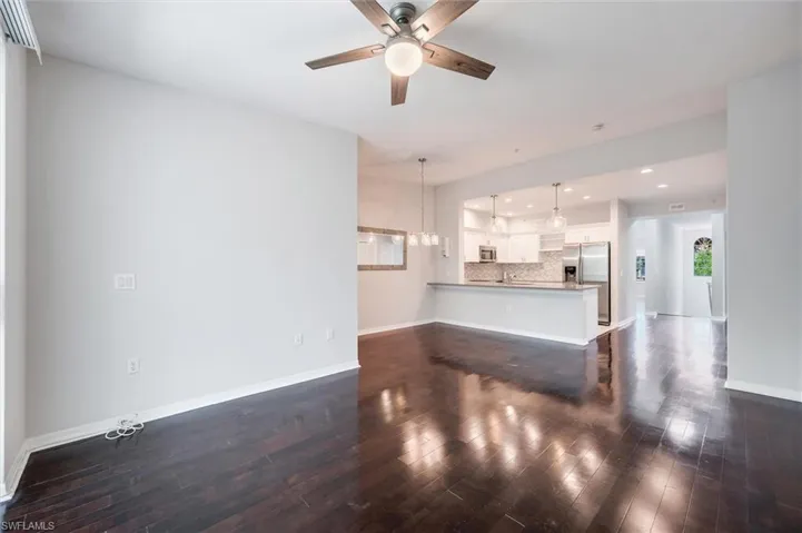 Unfurnished living room with a ceiling fan, dark wood-type flooring, and recessed lighting