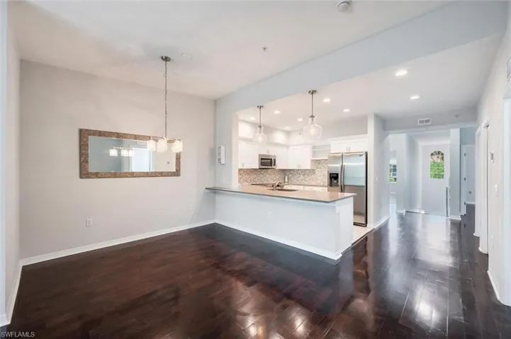 Kitchen with stainless steel appliances, a peninsula, dark wood-style flooring, and recessed lighting