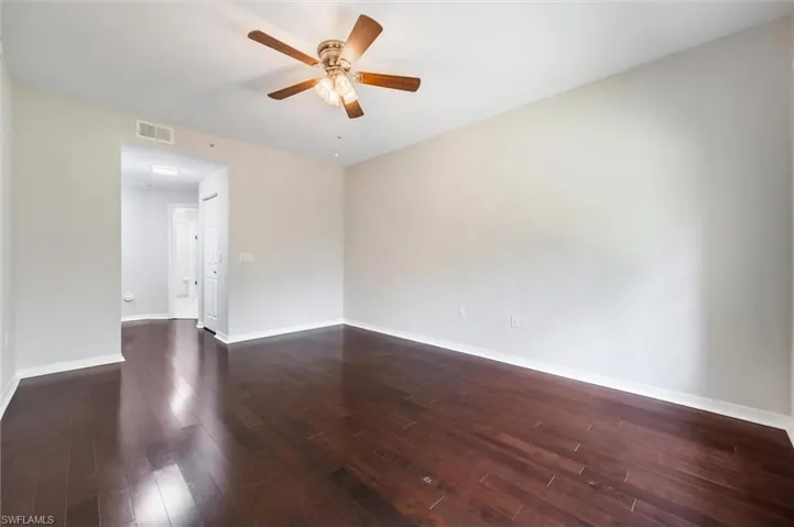 Empty room featuring dark wood-style flooring and ceiling fan