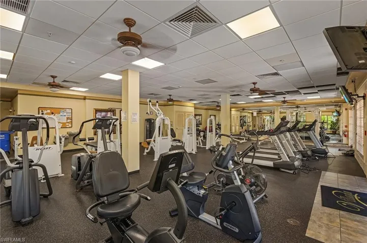 Gym with ceiling fan and a paneled ceiling