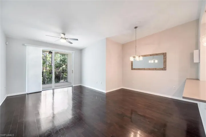 Unfurnished room featuring dark wood finished floors, ceiling fan, and a chandelier