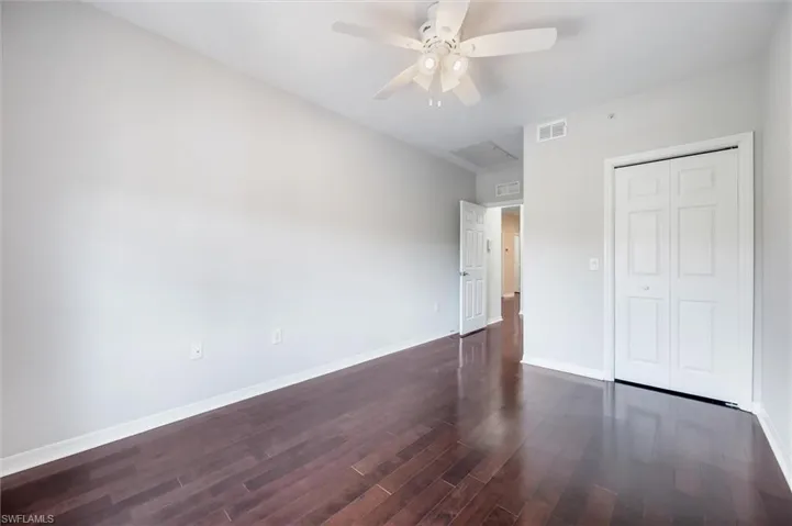 Unfurnished bedroom featuring dark wood-style flooring, a closet, and ceiling fan