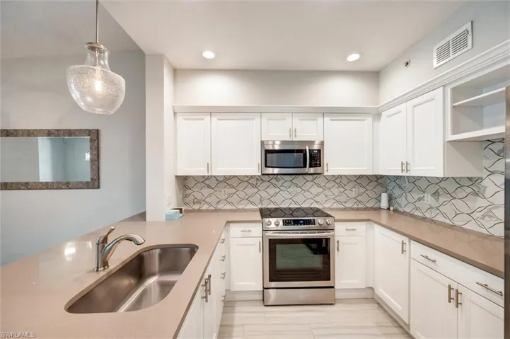 Kitchen featuring appliances with stainless steel finishes, white cabinetry, open shelves, decorative backsplash, and pendant lighting