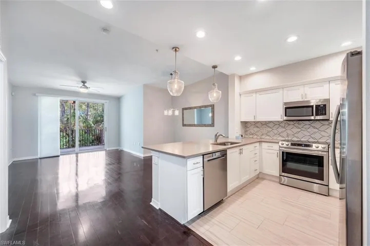 Kitchen featuring stainless steel appliances, white cabinets, backsplash, open floor plan, and a peninsula