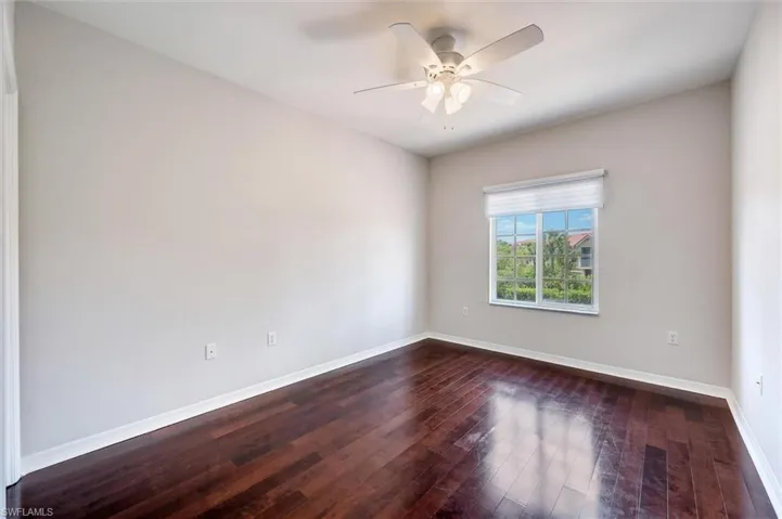 Unfurnished room with dark wood finished floors and ceiling fan