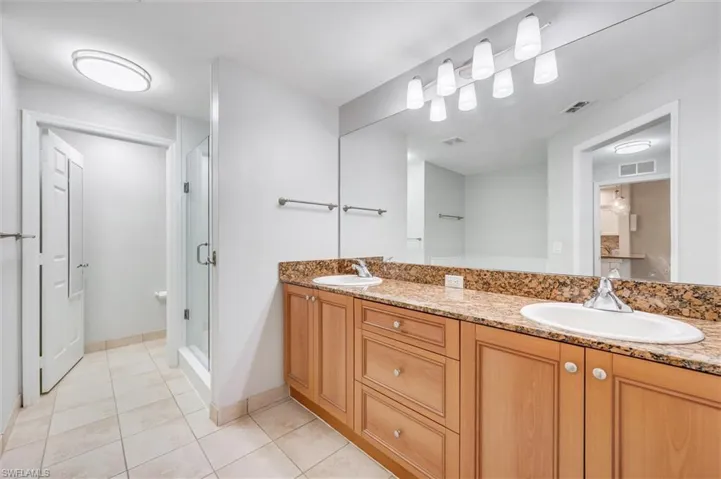 Full bathroom featuring double vanity, tile patterned floors, and a shower stall