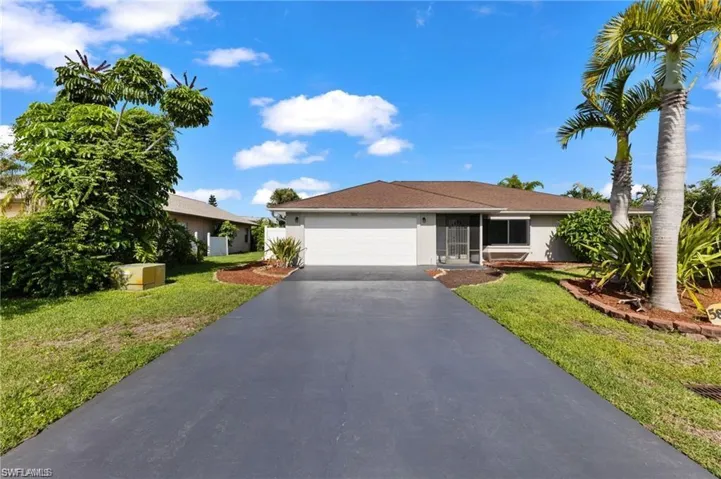 Ranch-style home featuring a garage and a front lawn