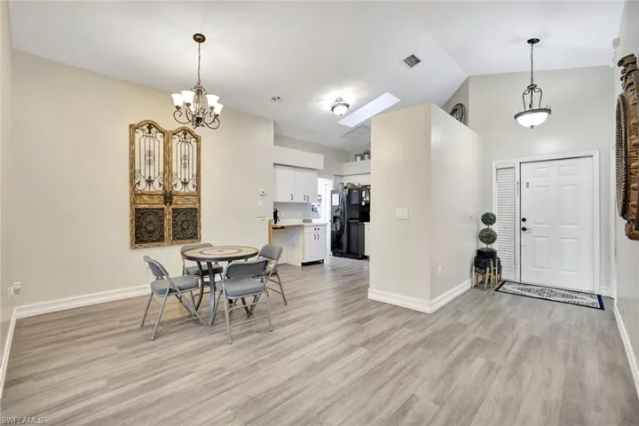Dining space featuring high vaulted ceiling, light wood finished floors, a skylight, and a chandelier