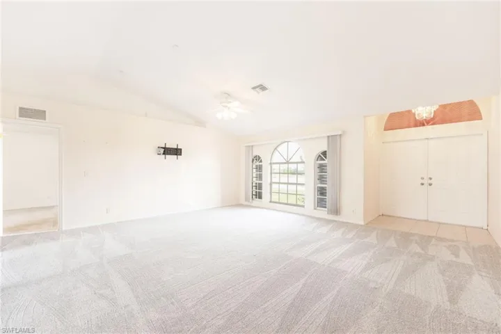 Unfurnished room with ceiling fan, light colored carpet, and vaulted ceiling