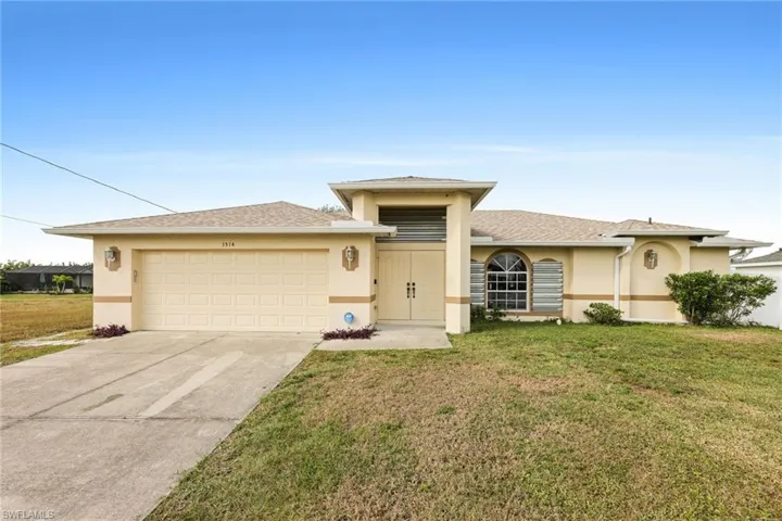 View of front facade featuring a garage and a front lawn