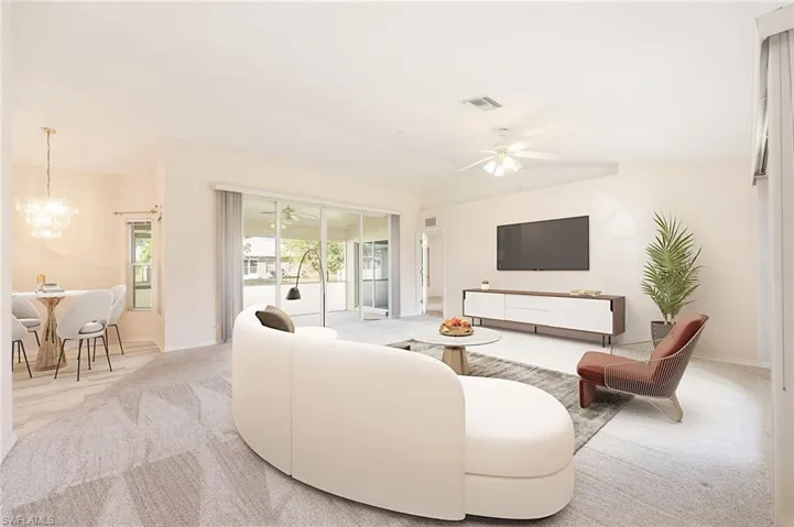 Carpeted living room featuring ceiling fan with notable chandelier