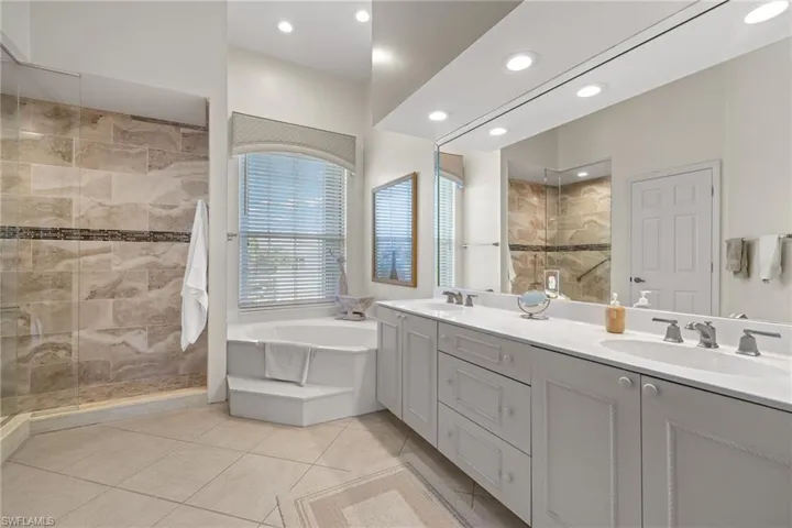 Bathroom featuring double vanity, a walk in shower, light tile patterned floors, a bath, and recessed lighting