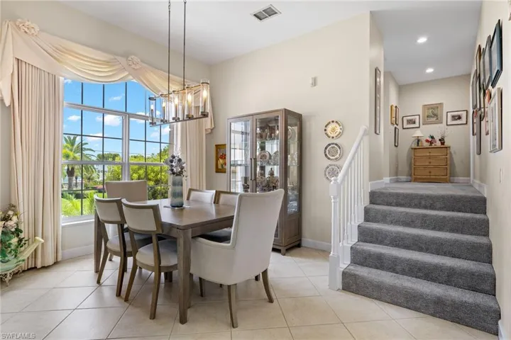 Dining area featuring a chandelier, light tile patterned flooring, stairs, and recessed lighting