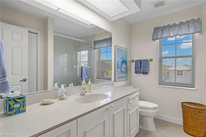 Bathroom with light tile patterned floors, vanity, and a stall shower