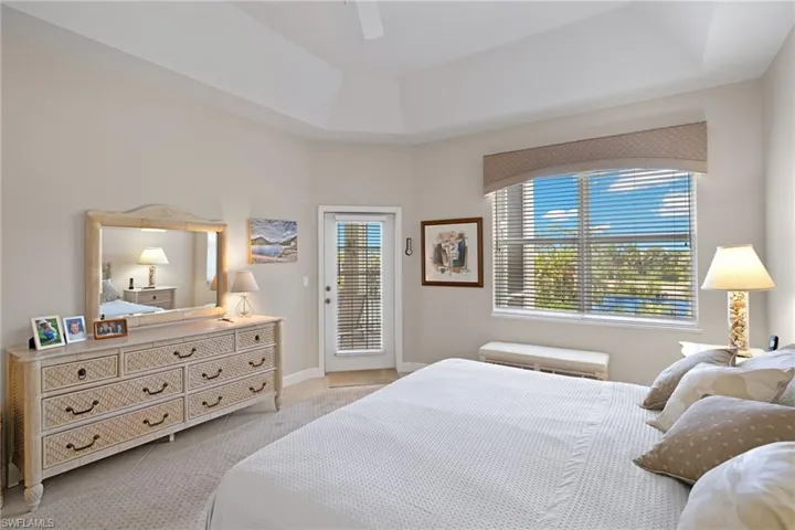 Bedroom featuring access to outside, a tray ceiling, and a ceiling fan
